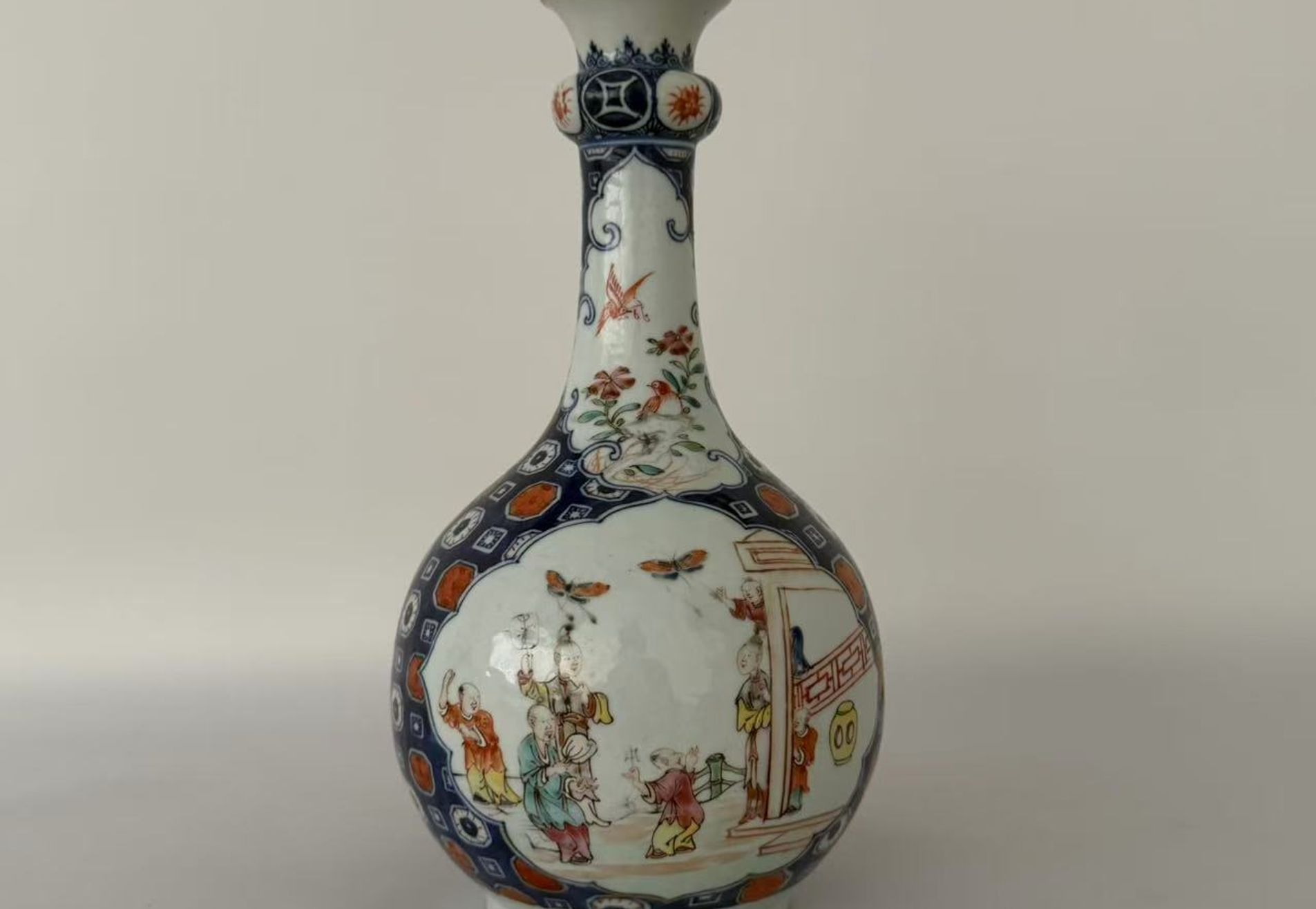 006 A Qianlong period blue-and-white and famille rose vase with iron-red and gilt decoration, featuring figural garden scenes and floral-and-bird motifs, in the form of a garlic-head bottle vase